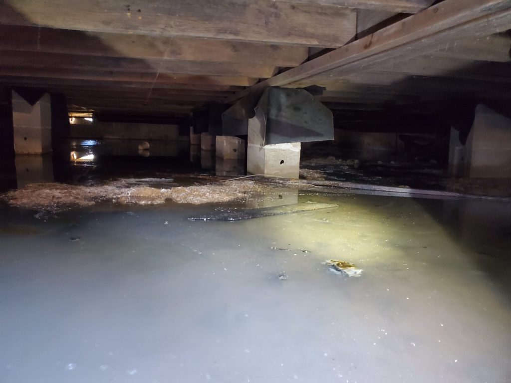 Standing water in a flooded crawl space after a Steubenville storm